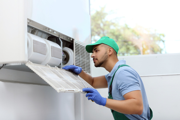 Professional technician maintaining modern air conditioner indoo
